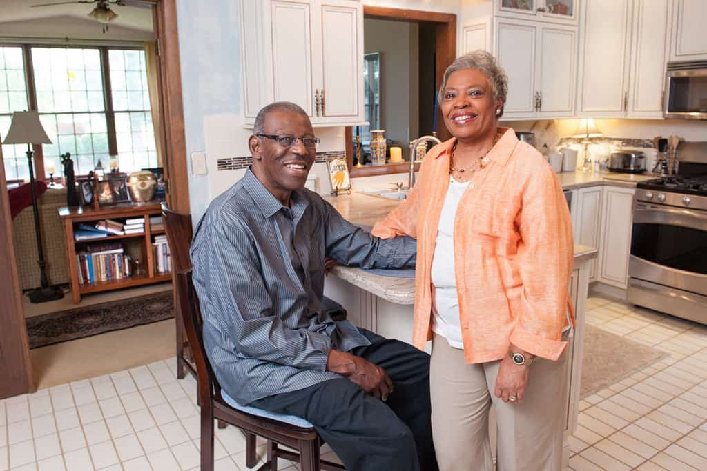 Husband and wife posing for a photo in their kitchen.
