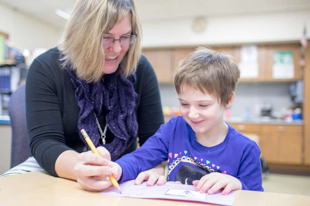 Teacher aiding a student with a writing exercise.