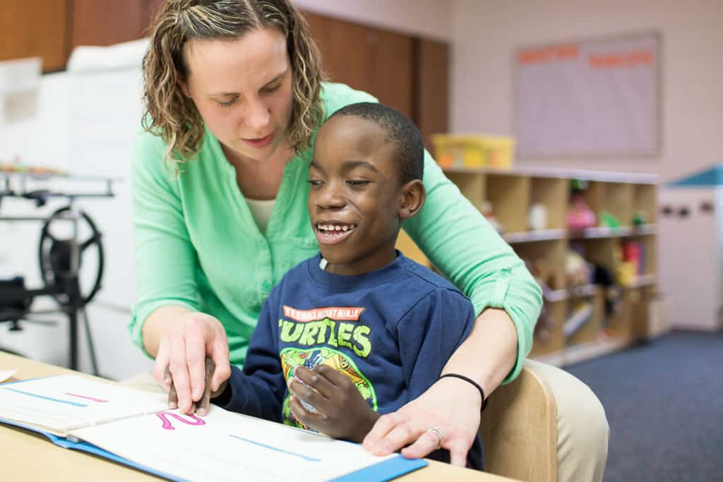 Teacher aiding her student in reading a book.