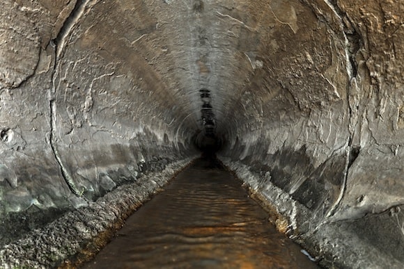 Deep sewage tunnel with liquid flowing inside.