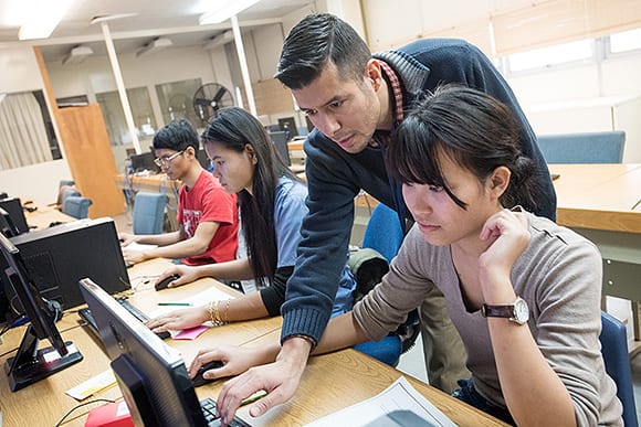 Teacher helping students in a computer lab