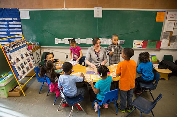 Instructor helping young children around a table