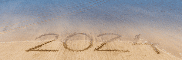 light blue water fading to a tan sandy beach with the year 2024 written in the sand.